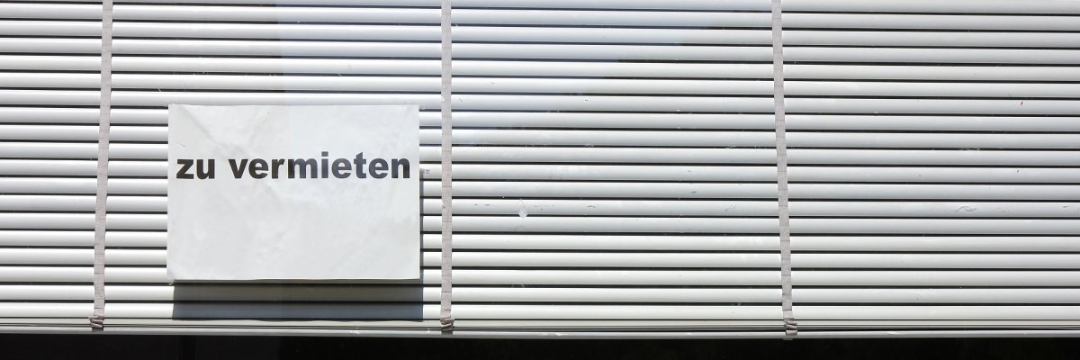 leerstehendes Ladenlokal An einem Schaufenster mit heruntergelassenen, weißen Jalousien klebt ein Hinweisschild mit dem Aufdruck "zu vermieten".