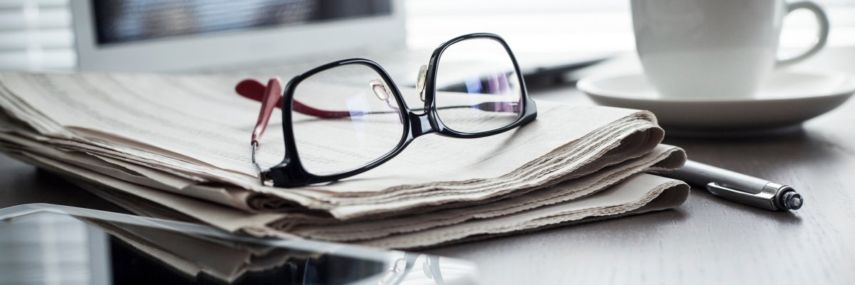 Newspaper with tablet on table