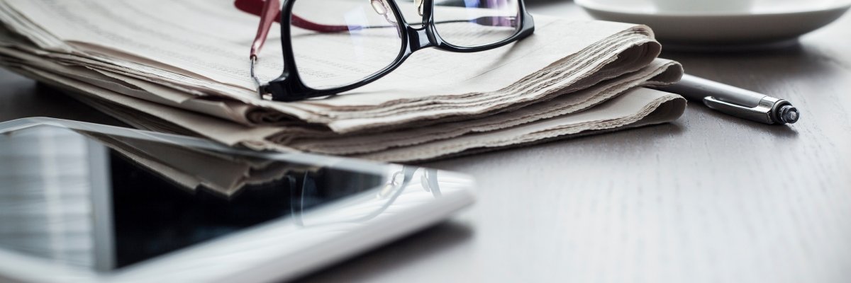 Newspaper with tablet on table Newspaper with tablet on table