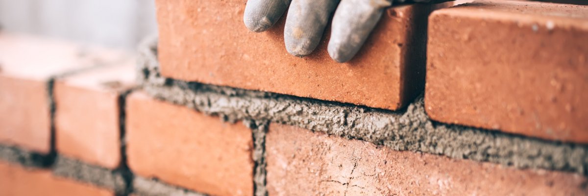 Close up of industrial bricklayer installing bricks on construct