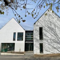 Ein modernes Gebäude mit weißem Klinker und schmalen Fenstern. Über der Eingangs-Drehtür steht in Großbuchstaben AMTSHAUS geschrieben.