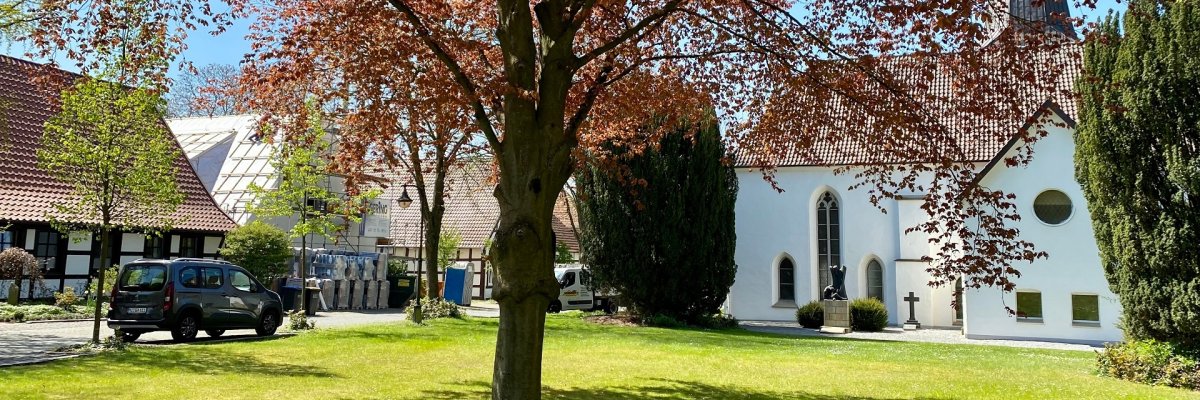 Kirche Dielingen Eine in eine Art Parklandschaft eingebettete weiße Kirche.
