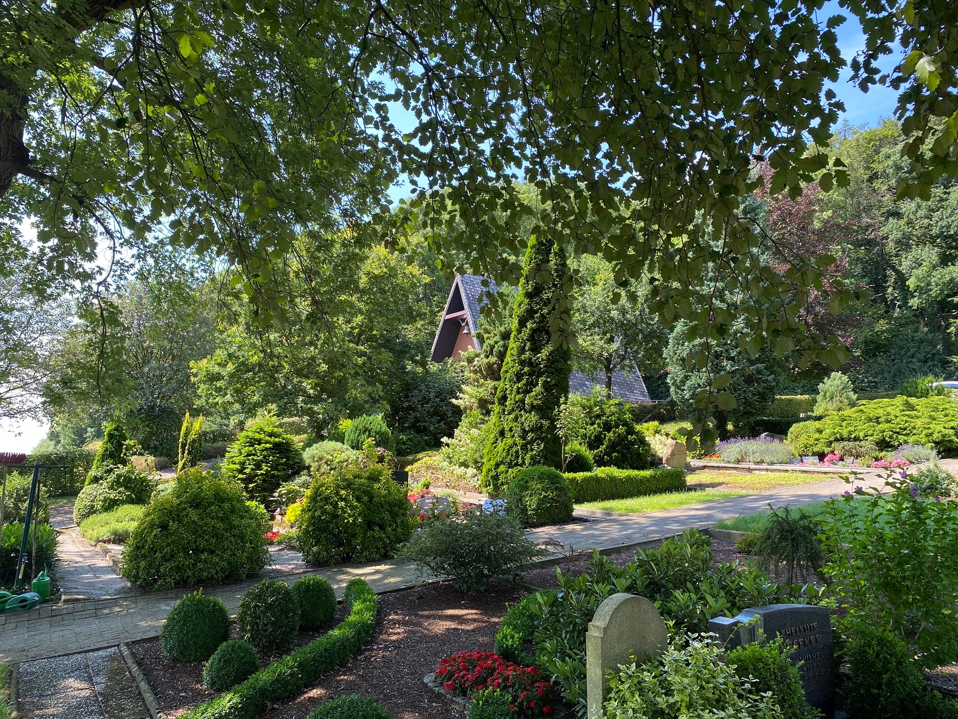 Ein am Hang gelegener Friedhof auf dem viele Gräber und im Hintergrund eine Kapelle zu sehen sind.