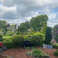 Ein Friedhof, auf dem im Vordergrund einige Gräber und im Hintergrund ein weißes Kapellengebäude.