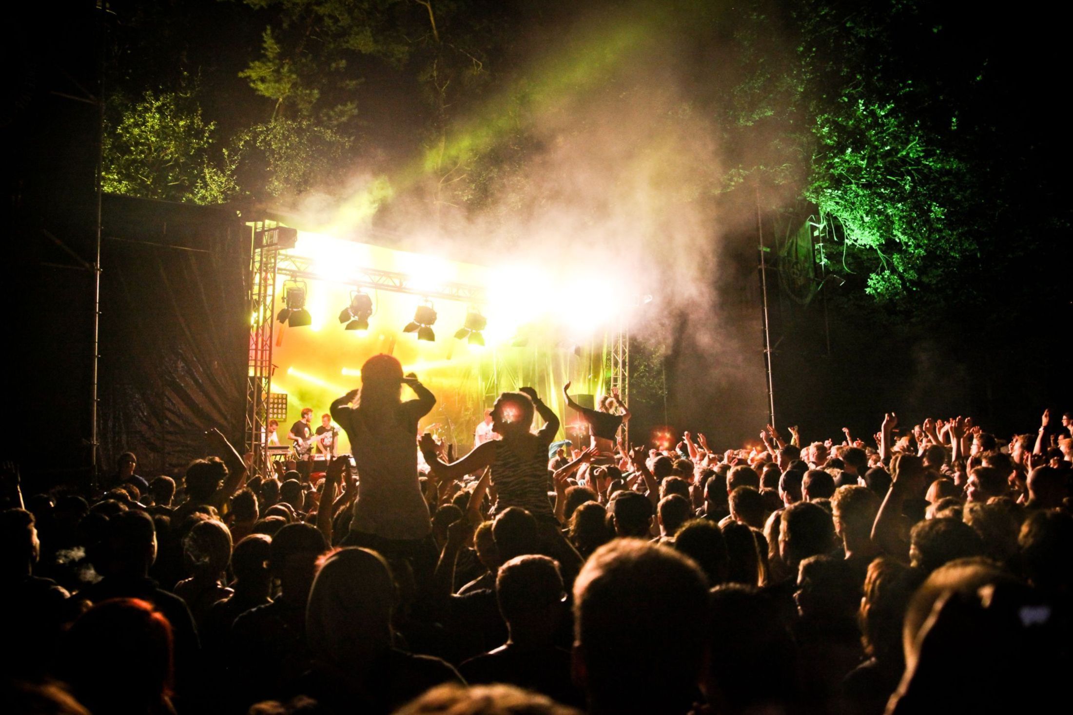 Festivalstimmung. Tausende Menschen stehen vor einer hellbeleuchteten Bühne.