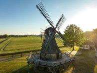 Mühle Levern Luftaufnahme Eine Drohnenaufnahme aus der Luft, die im Vordergrund eine historische Windmühle zeigt und Felder im Hintergrund.
