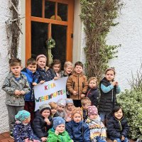 Kinder eines Kindergartens, die ein Schild mit der Aufschrift "Kita Wiesenpiraten" hochhalten.