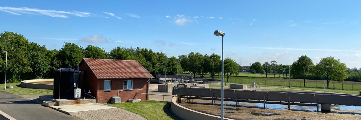 Kläranlage Wehdem Blick auf zwei Klärbecken und ein rotes Pumpenhäuschen einer Kläranlage.