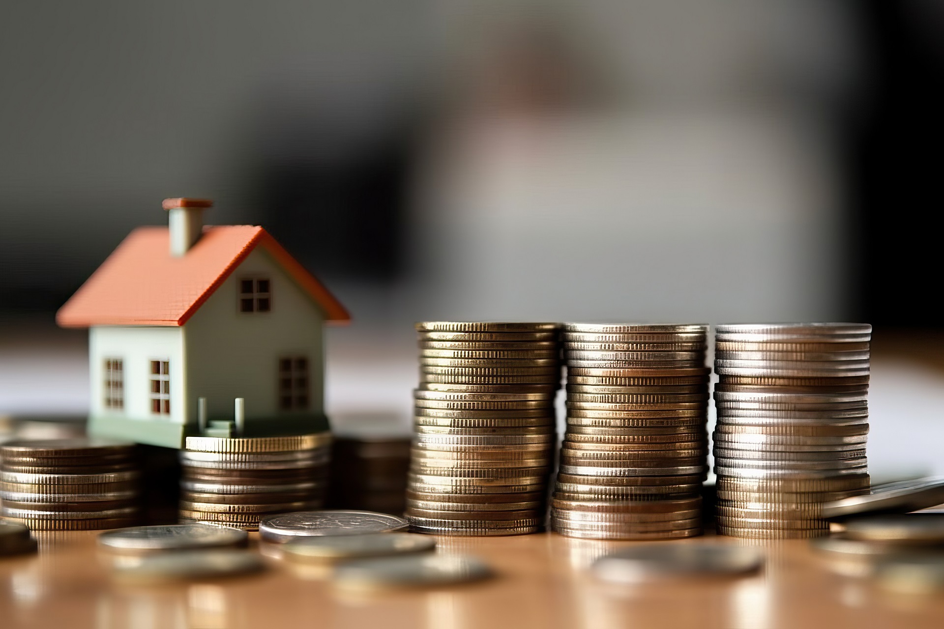 Photo of a house perched on a mound of golden coins, symbolizing