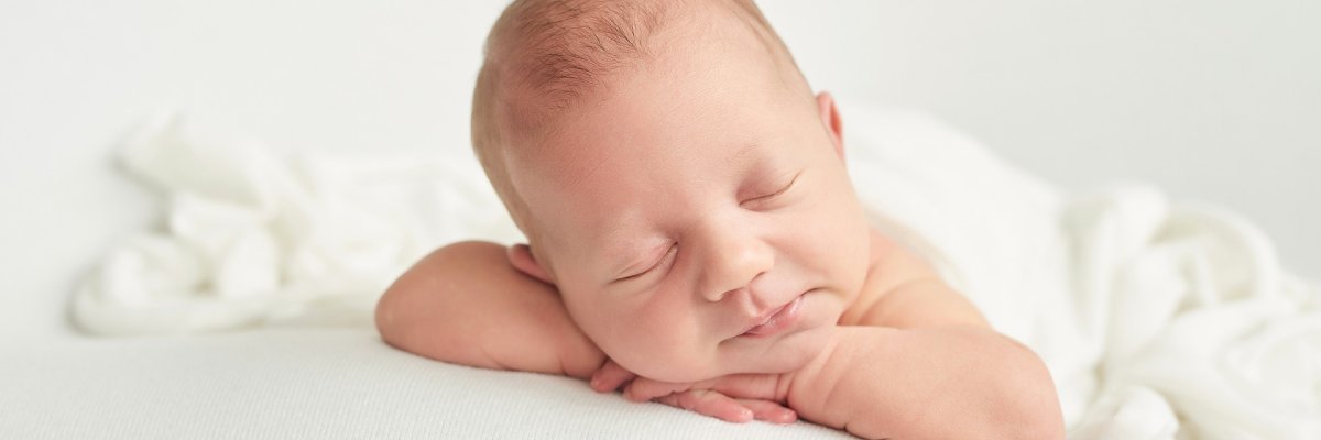 Ein Baby, das mit geschlossenen Augen lächelt. 
