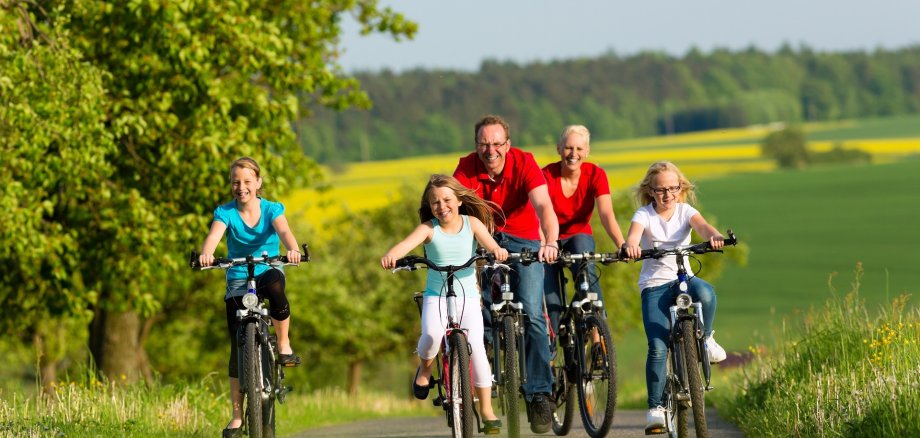 Eine Familie mit drei Kindern, die auf Fahrrädern unterwegs ist.