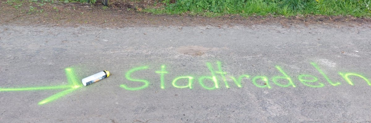 STADTRADELN Ein auf die Straße in neon-grün gesprühter Schriftzug "Stadtradeln".