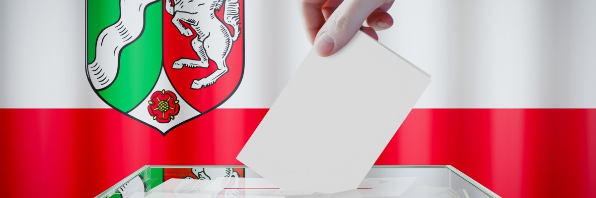 North Rhine-Westphalia flag, hand dropping ballot card into a box - voting/ election in Germany concept - 3D illustration
