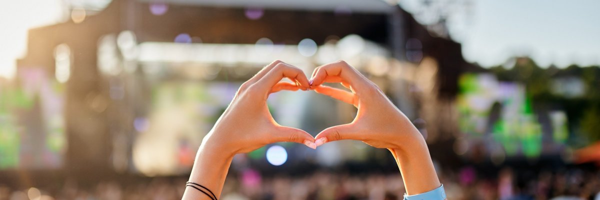 Concertgoer forms heart shape with hands at beachside music festival, crowd enjoys live performance in sunset, love symbol gesture at summer event, youth celebration of art, outdoor entertainment. Concertgoer forms heart shape with hands at beachside music festival, crowd enjoys live performance in sunset, love symbol gesture at summer event, youth celebration of art, outdoor entertainment.