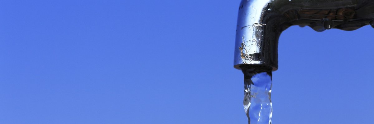 Wasserhahn Nahaufnahme eines Wasserhahns, aus dem ein gleichmäßiger Wasserstrahl fließt. Der Hintergrund ist unscharf und in Blautönen gehalten, wodurch der fließende Wasserstrahl und der glänzende Metallhahn im Vordergrund besonders hervorgehoben werden.