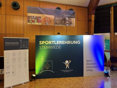 Bühne einer Sportlerehrung in einer holzvertäfelten Halle. Im Mittelpunkt steht eine beleuchtete Tafel mit der Aufschrift „Sportlerehrung Stemwede“, daneben Banner der Gemeinde Stemwede und des Gemeindesportverbands Stemwede.
