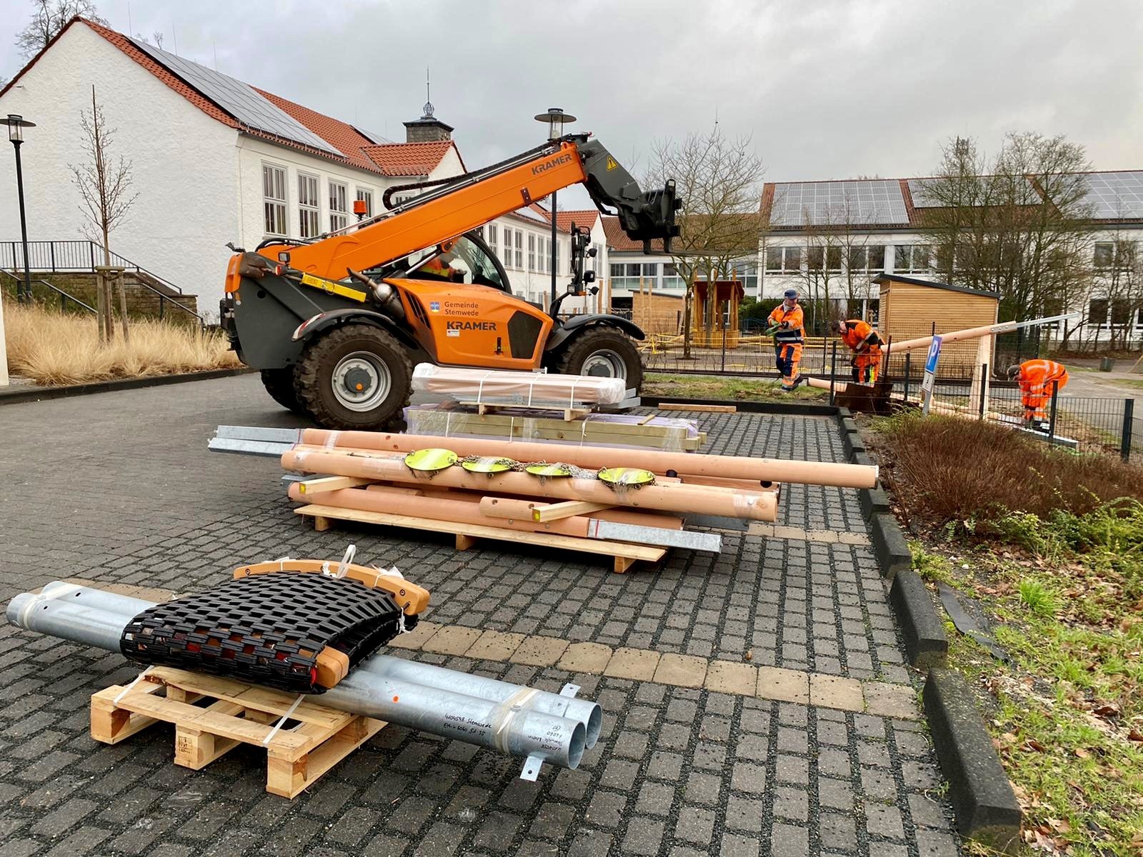 Arbeiter der Gemeinde montieren Spielgeräte, die gerade angeliefert wurden. 