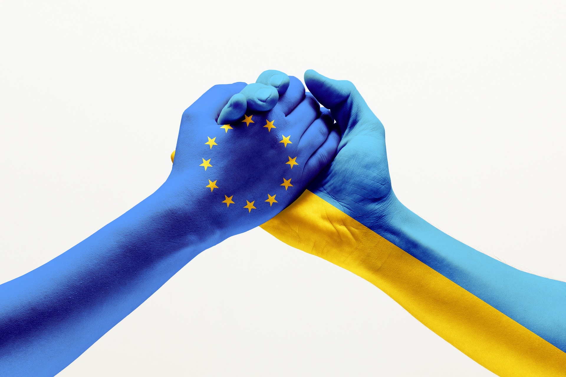 eine in den europäischen Farben bemalte Hand hält eine Hand, die in den ukrainischen Nationalfarben bemalt ist. 