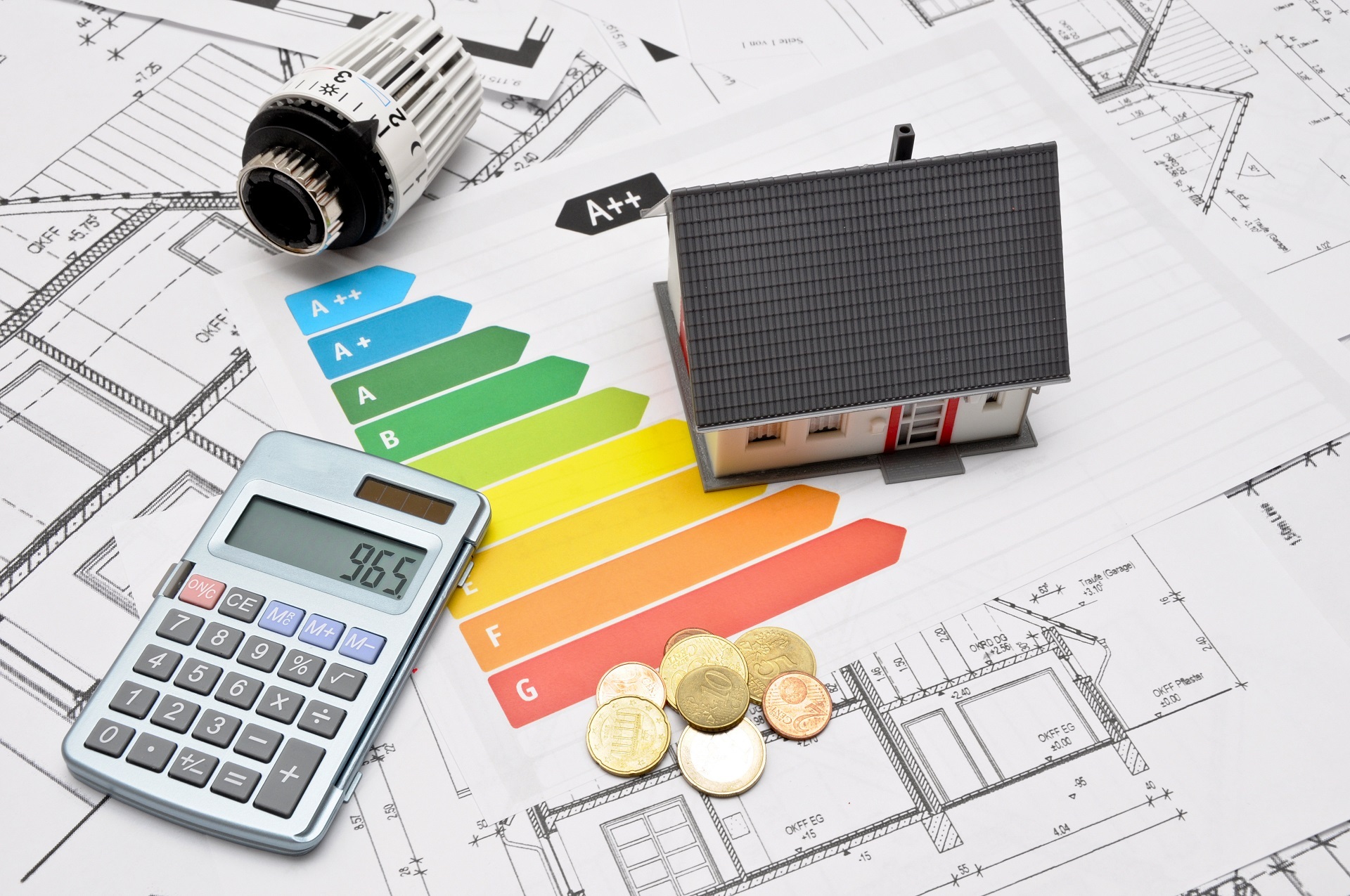 Baupläne, Taschenrechner und noch mehr - Unterlagen eines Energieberaters liegen auf einem Tisch. 