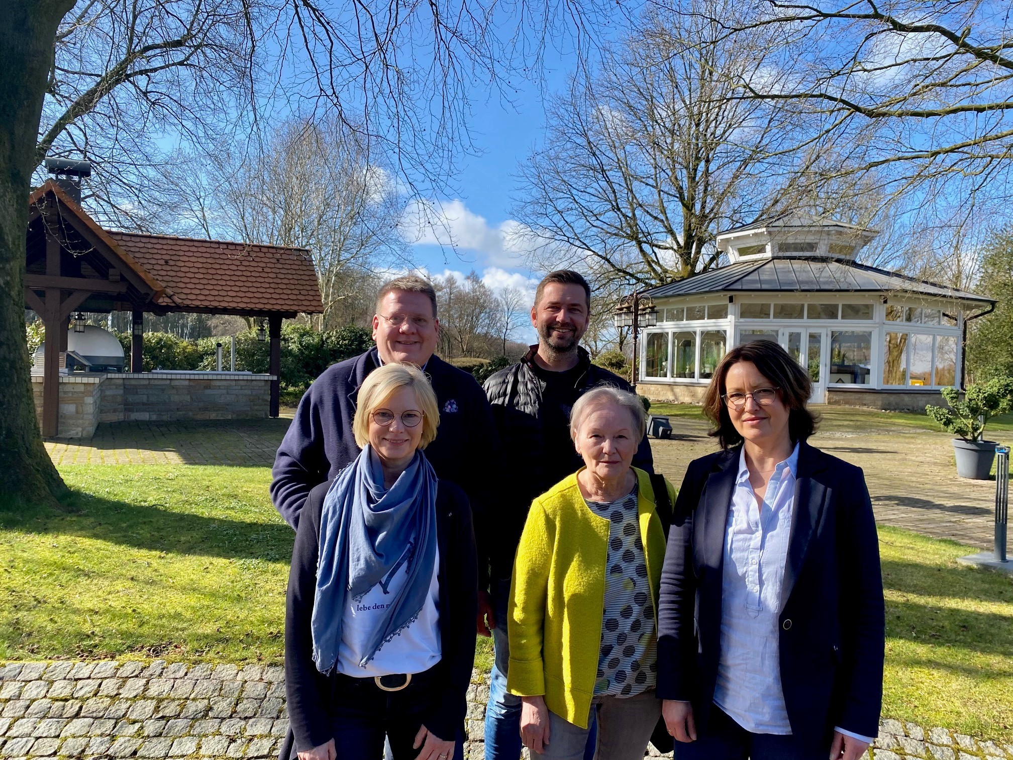 Gruppenfoto in einer parkähnlichen Fläche: drei Frauen stehen im Vordergrund, zwei Männer hinter ihnen. 