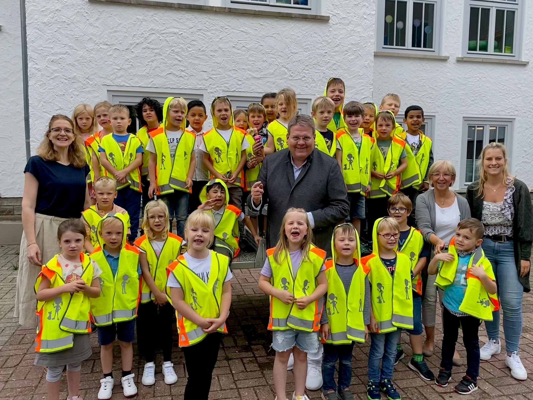Gruppenfoto mit vielen Kindern in knallgelben Warnwesten. 