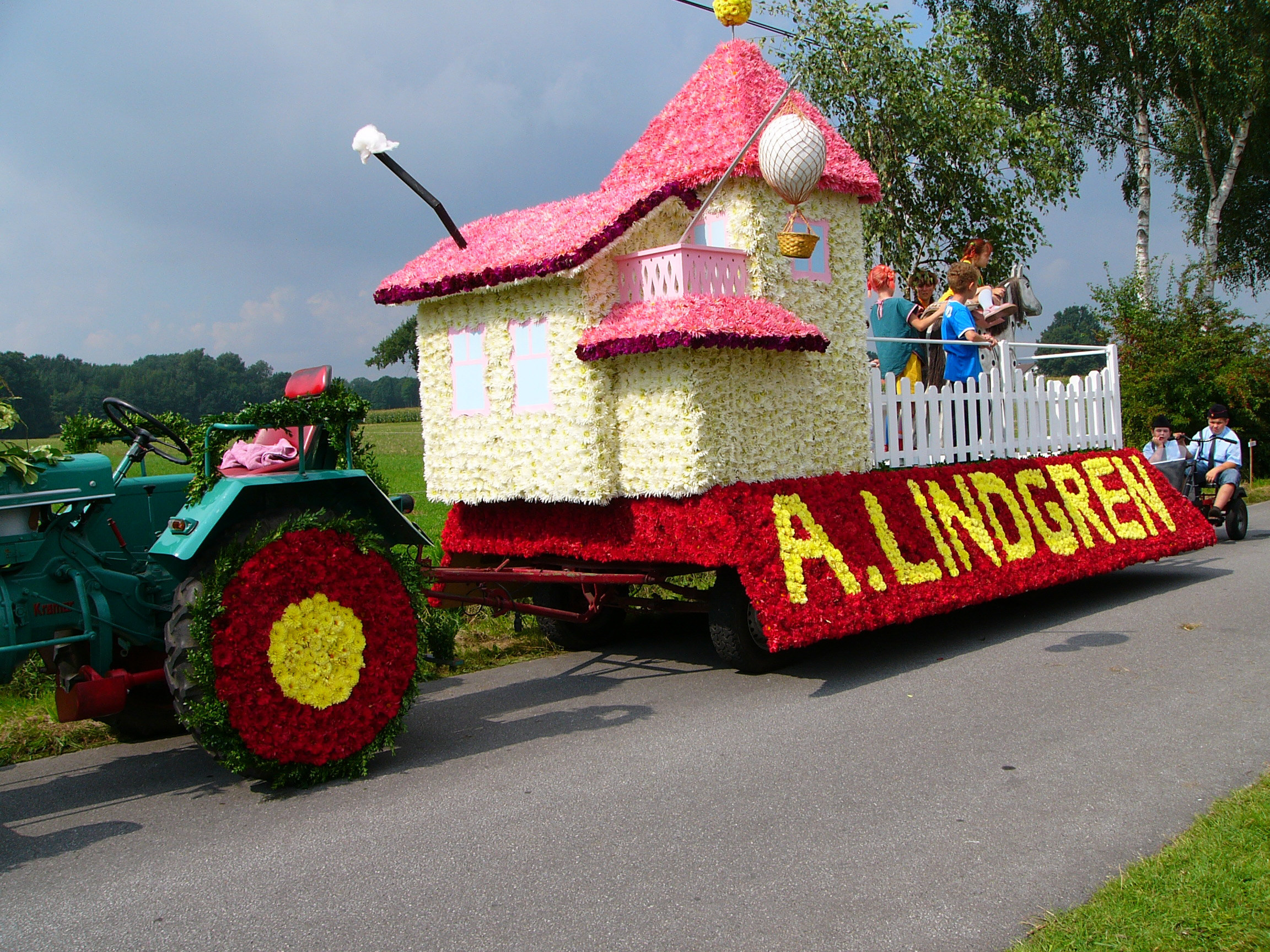 Ein mit vielen Blumen geschmückter Traktor, der bim Blumenkorso mitfährt. 