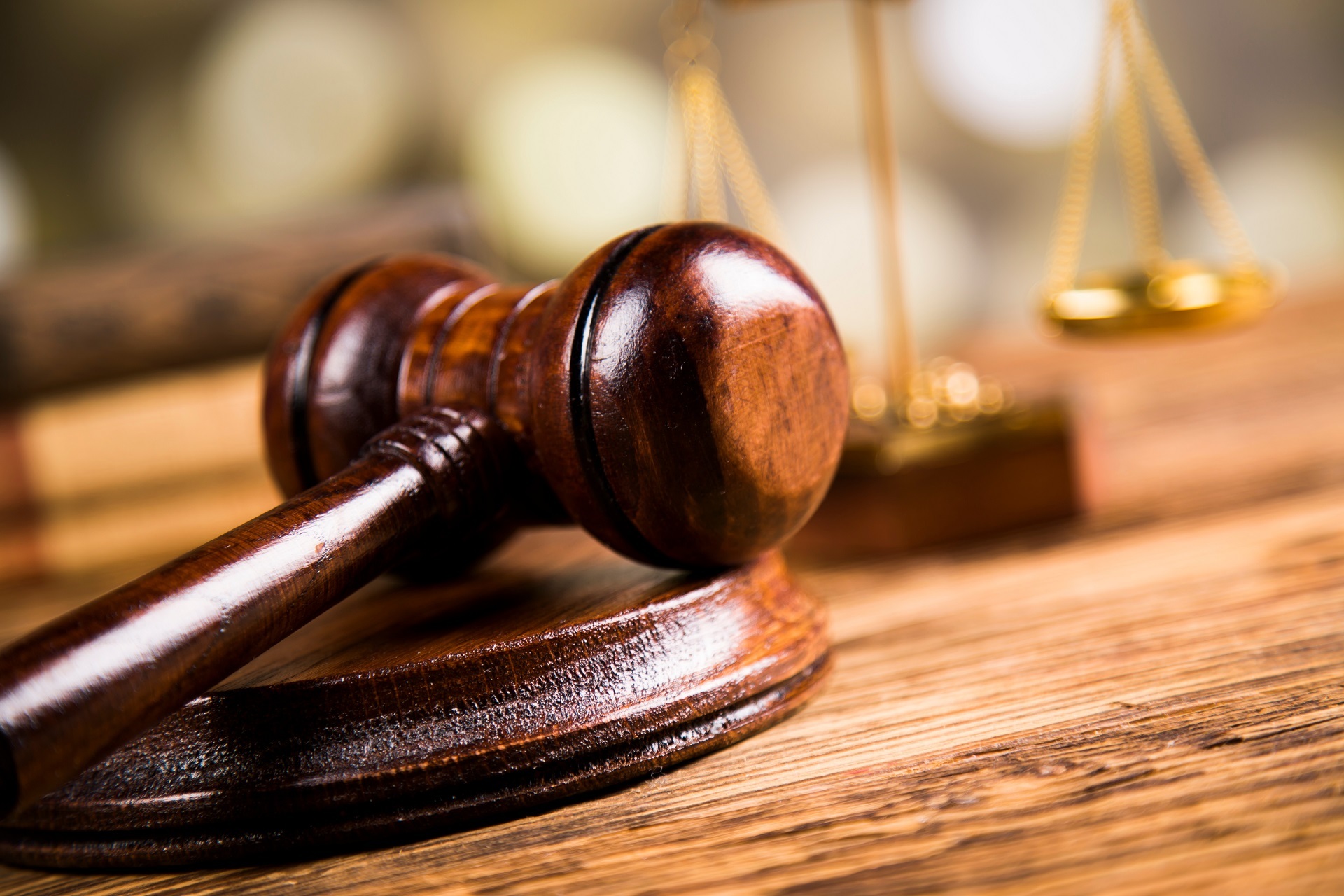 Ein Richterhammer und im Hintergrund eine Waage, als Zeichen der Justiz. 