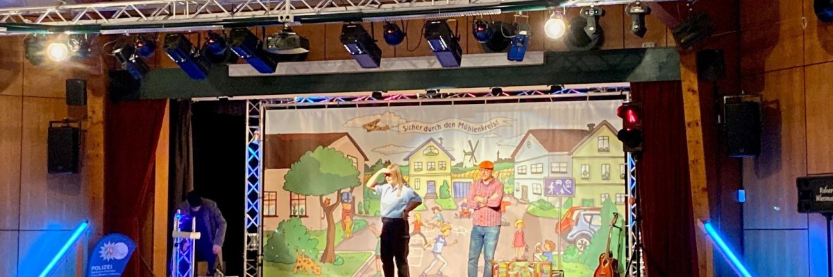 Eine Veranstaltung, bei der viele Kinder im Publikum sitzen, während auf der Bühne zwei Menschen etwas vorführen.