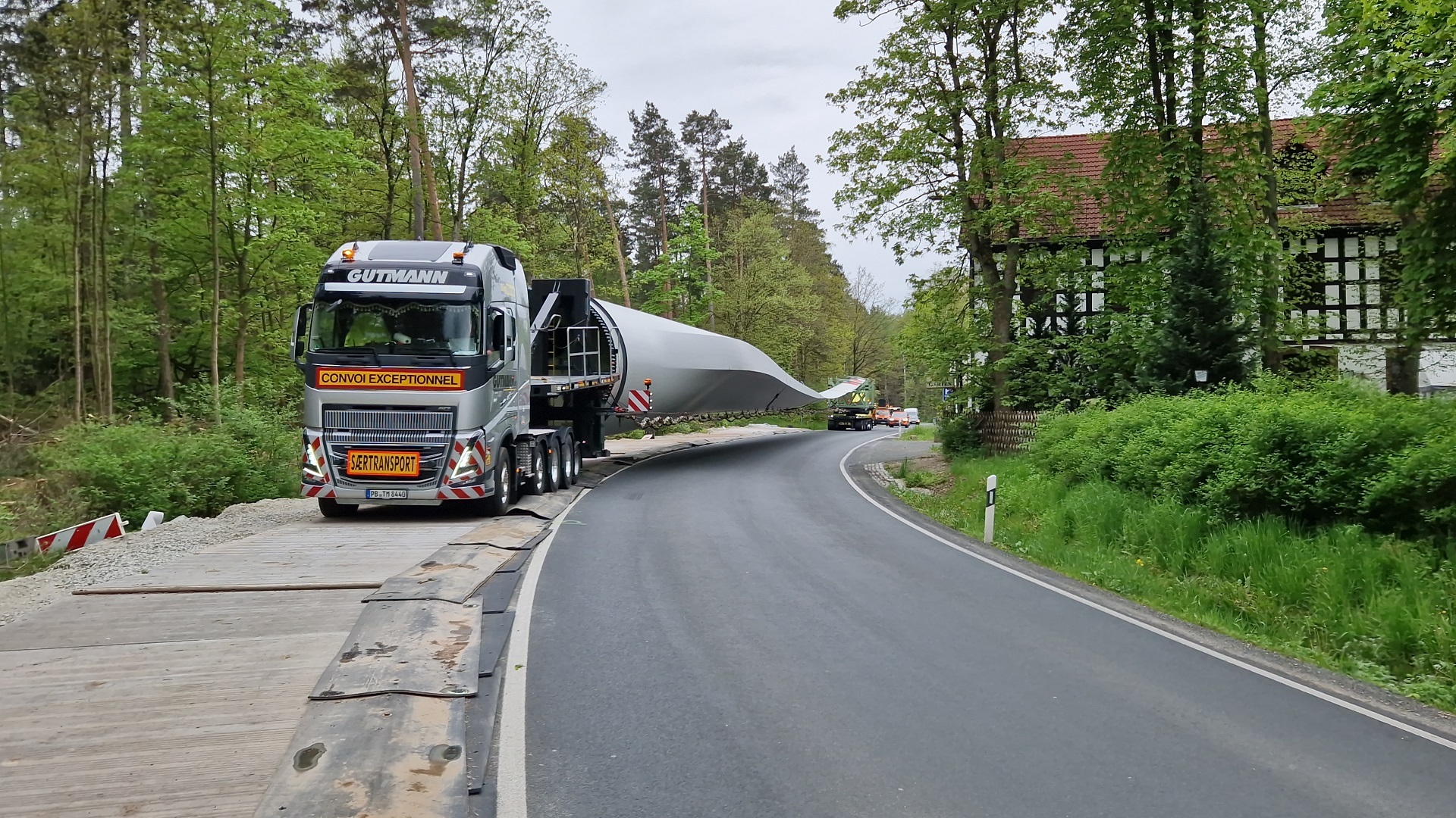 Ein Schwertransport, der ein Rotorblatt transportiert, fährt eine Bergstraße hoch. 