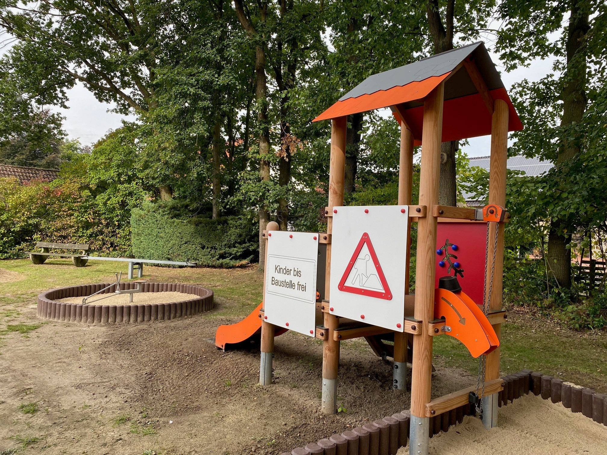 Ein Kletterturm auf einem Spielplatz. Im Hintergrund ist ein Sandkasten zu sehen.