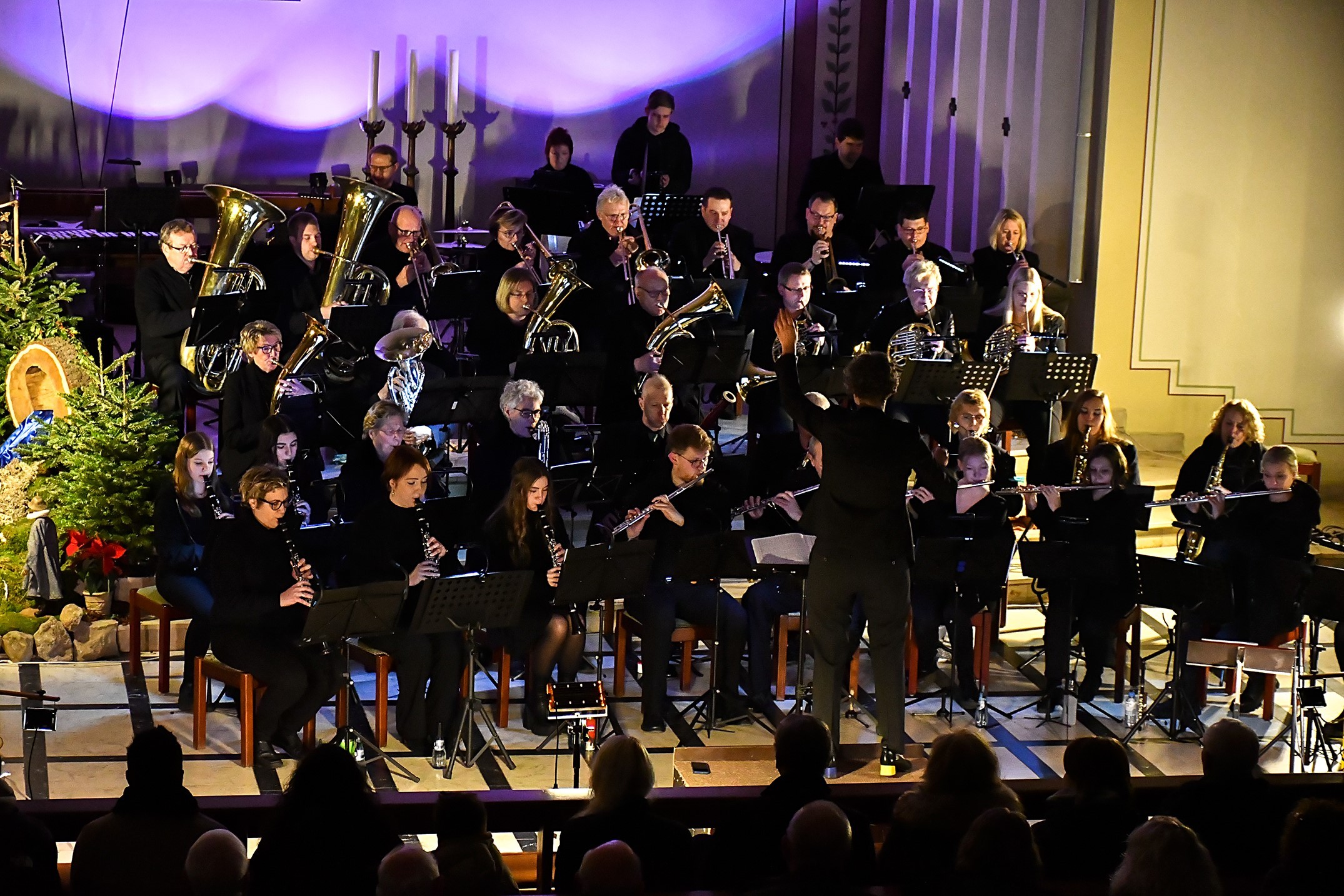 Ein Blasorchester auf einer Bühne, stimmungsvoll durch blaues Licht beleuchtet.