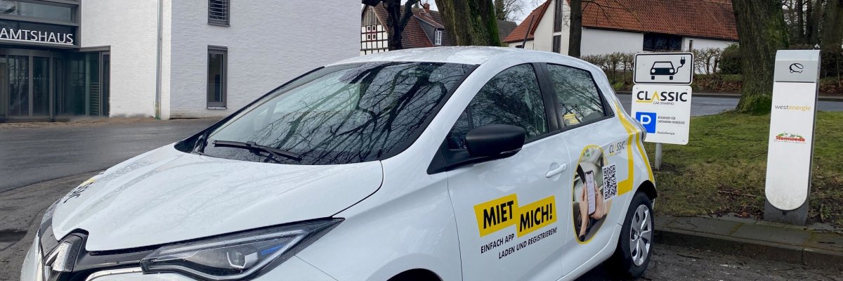 Ein E-Fahrzeug an einer Ladesäule vor einem weißen Gebäude.