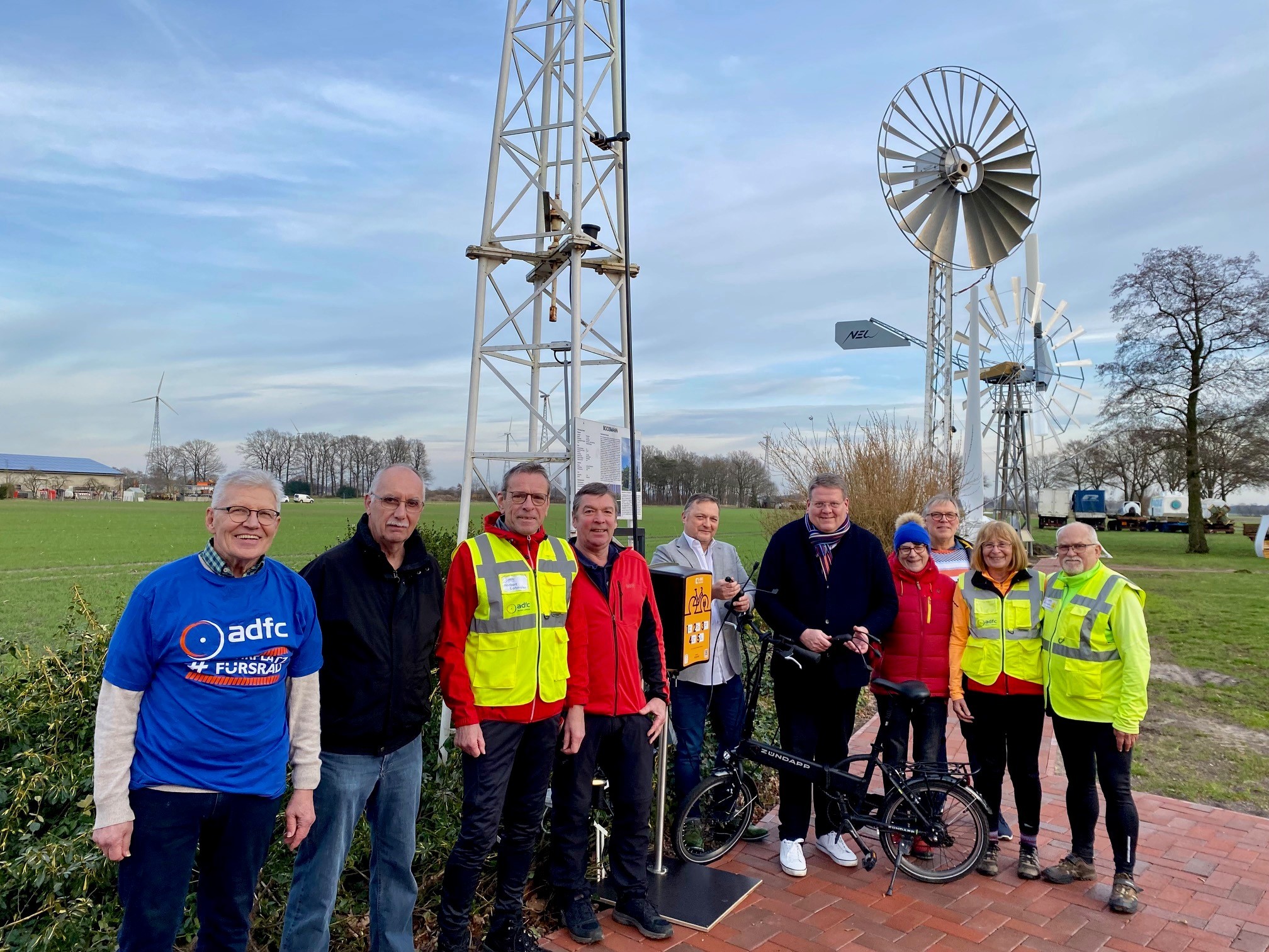 Gruppenfoto mit zehn Menschen vor einer Ladesäule. 