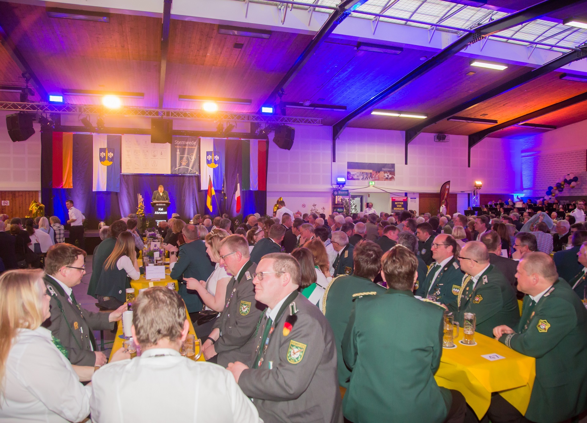 Eine Festveranstaltung in einer Festhalle mit zahlreichen Gästen im Publikum. 