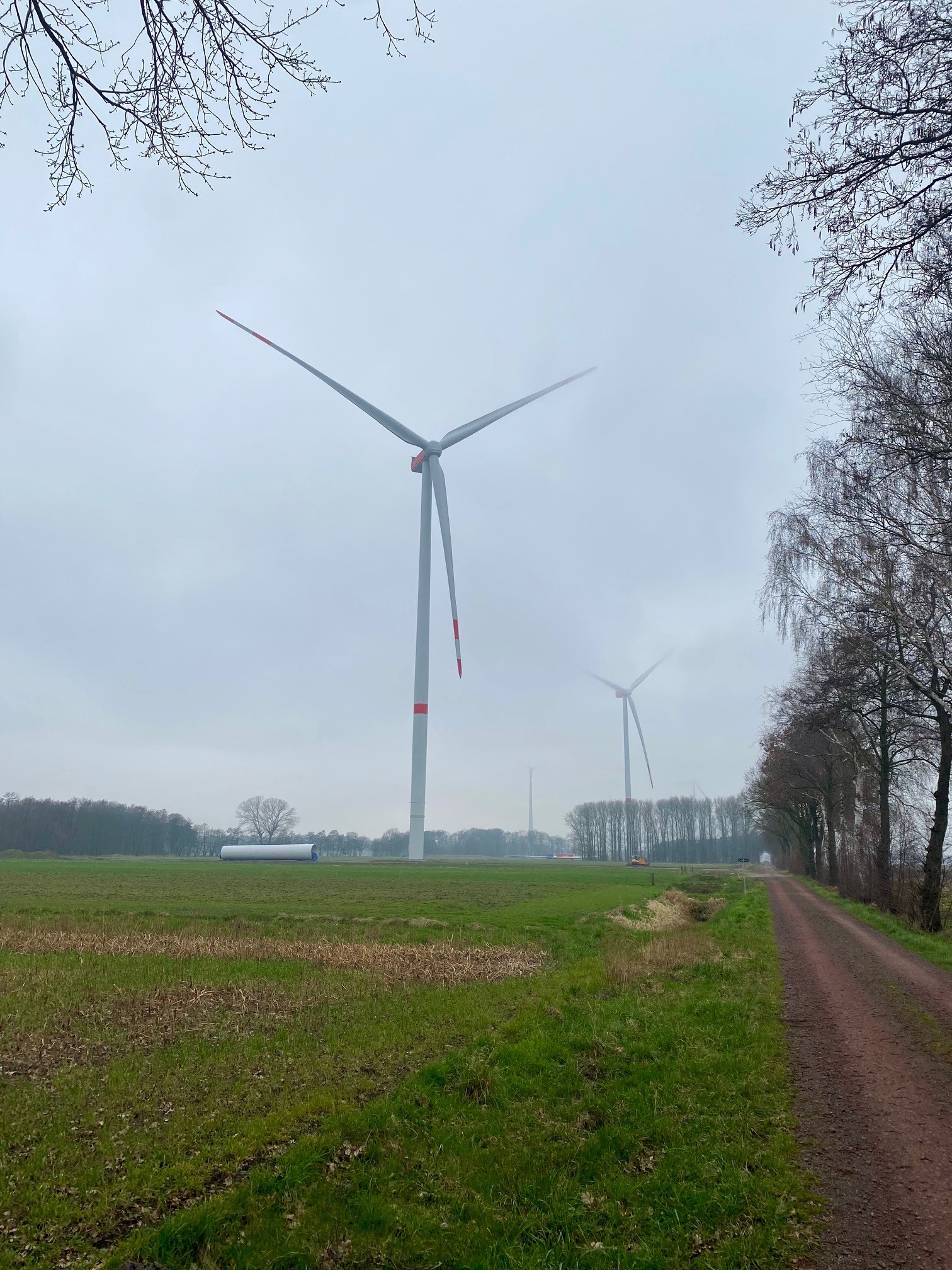 Ein Windrad bei diesigem Wetter. Im Hintergrund ist ein weiteres Windrad zu erkennen.