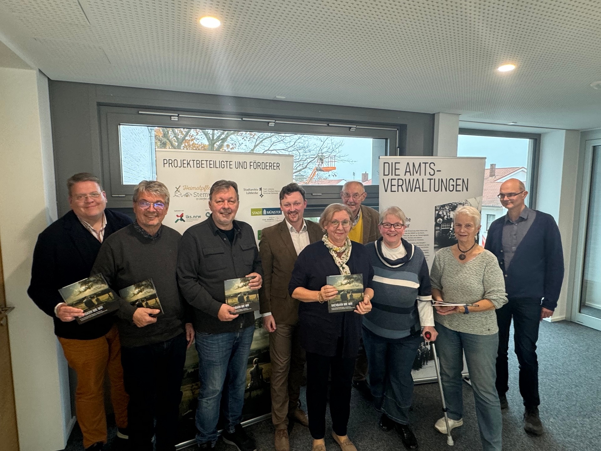 Sechs Männer und Frauen, die sich zum Gruppenfoto aufgestellt haben und jeweils ein Buch "Nachbarn wie wir" in den Händen halten.