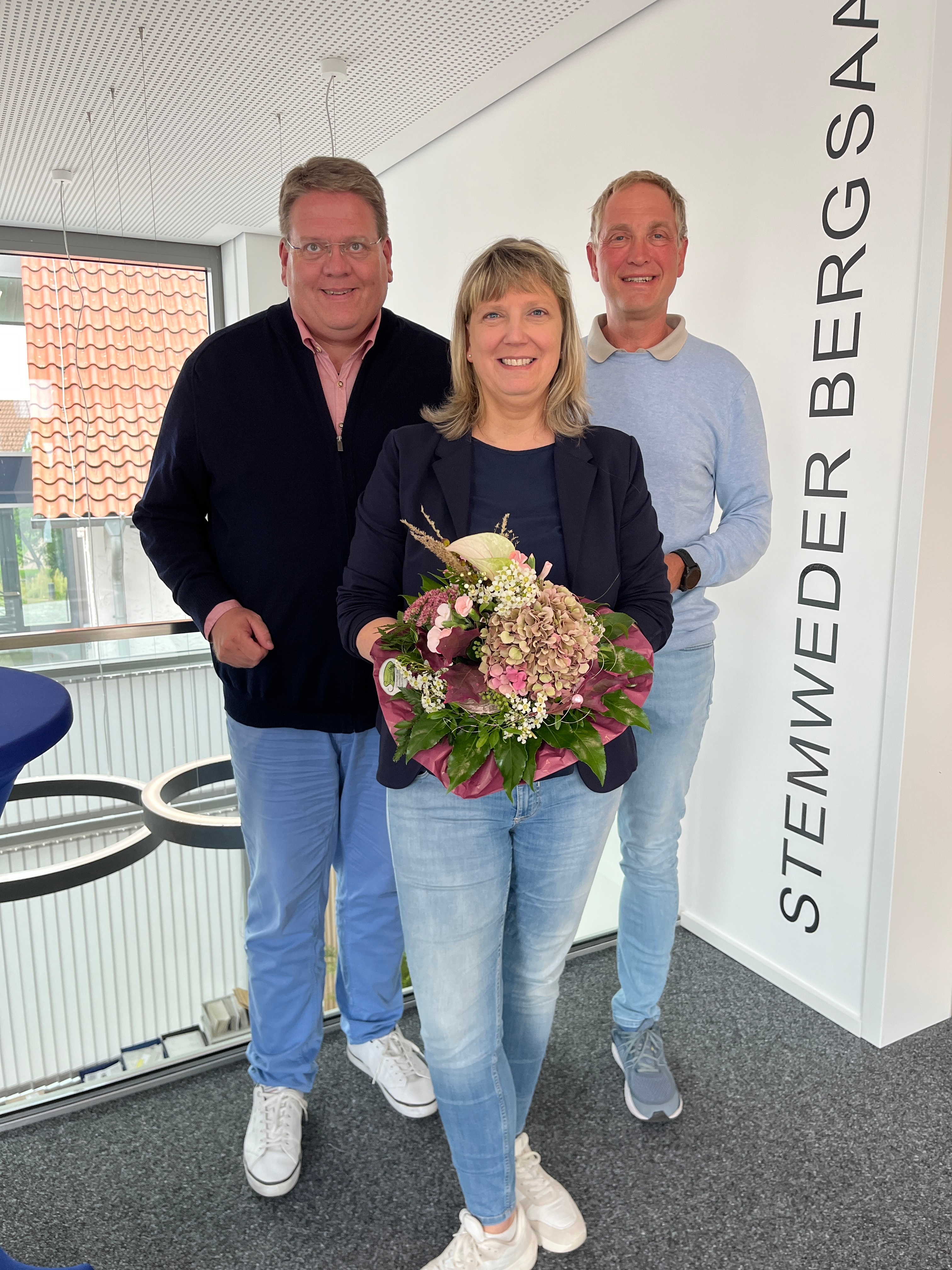 Schulleiterin Imke Sundermeier hält einen Blumenstrauß in den Händen. Bürgermeister Kai Abruszat und sein allgemeiner Vertreter Jörg Bartel steht hinter ihr.