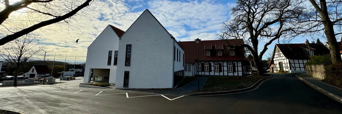 Ein weißer Gebäudekomplex. Zwei neue, weiße Gebäudefronten, die an ein historisches Fachwerkhaus angrenzen.