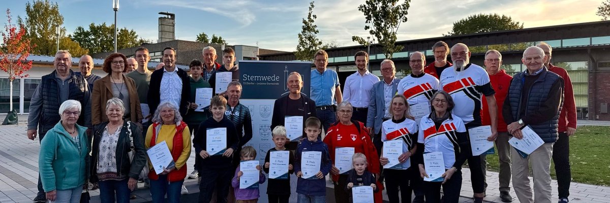 Ehrung STADTRADELN 2025 Zahlreiche Personen, zum Teil im sportlichen Outfit, die sich vor einem Gebäude für ein Gruppenfoto aufgestellt haben und Urkunden vor dem Körper halten.
