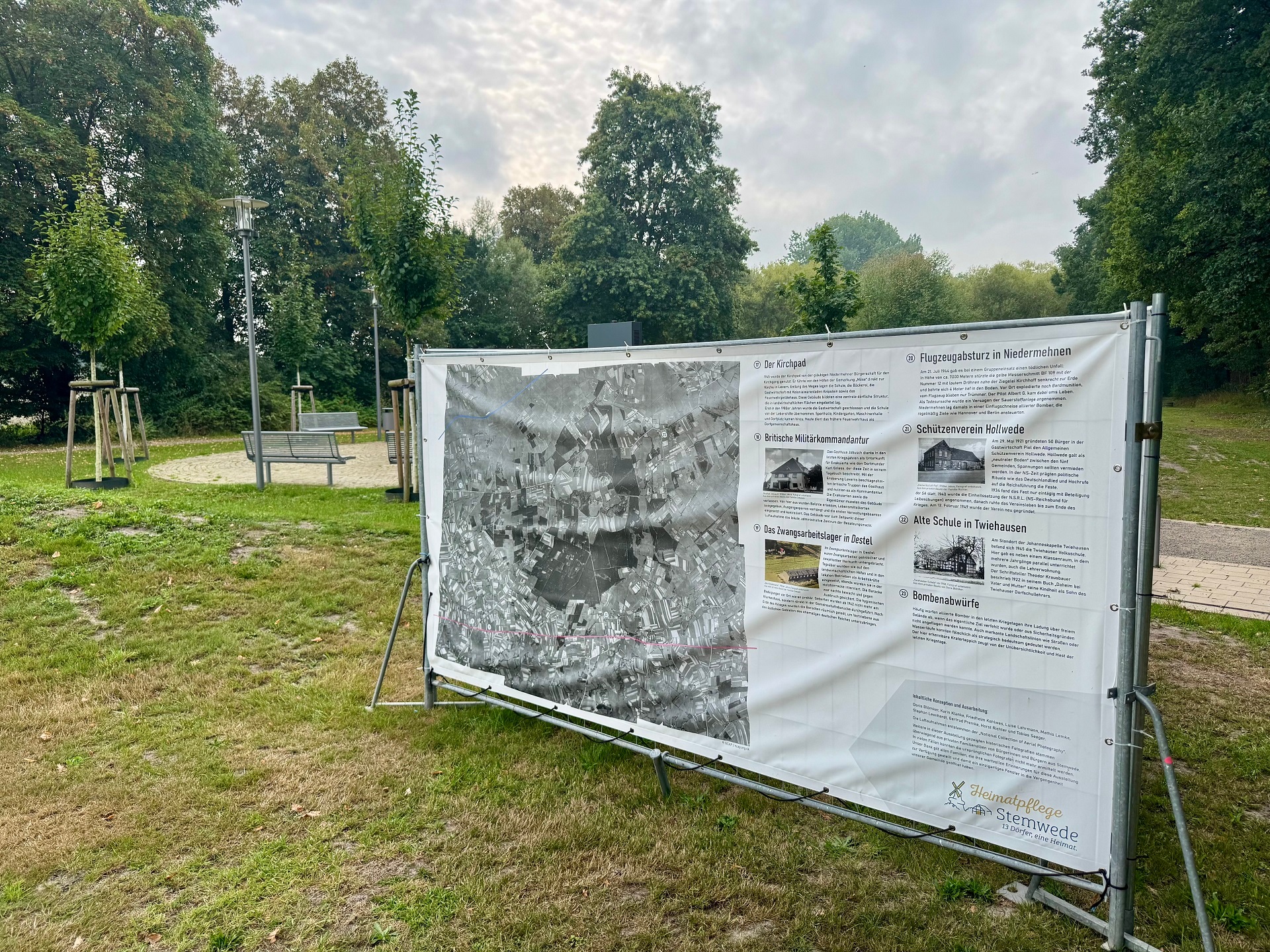 Großflächige Plakate an Bauzäunen in einem Park.