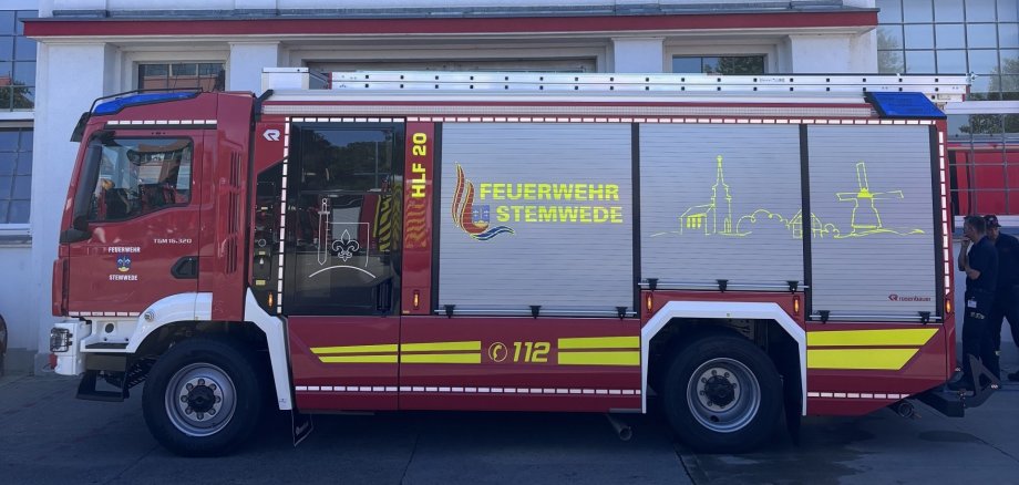 HLF 20 Oppenwehe Ein rotes Hilfeleistungslöschgruppenfahrzeug (HLF 20) der Feuerwehr Stemwede steht vor dem Werk des Feuerwehrfahrzeugherstellers Rosenbauer. Auf der Fahrzeugseite sind das Wappen der Gemeinde Stemwede, die Aufschrift „Feuerwehr Stemwede“ sowie eine stilisierte Silhouette mit Kirche und Windmühle zu sehen. Auf dem Dach ist eine Steckleiter montiert. Im Hintergrund befindet sich das Betriebsgebäude mit großen Fenstern und dem Schriftzug „Rosenbauer“.