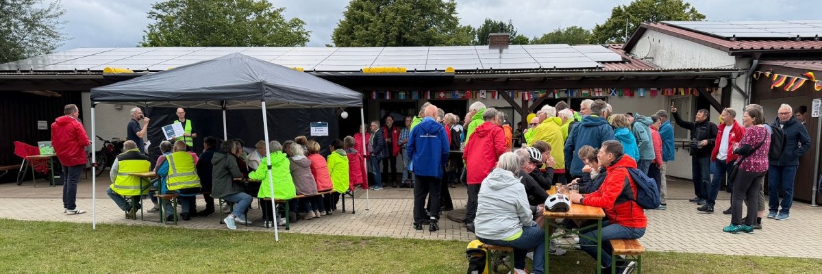 Zahlreiche Teilnehmerinnen und Teilnehmer des STADTRADELN-Abschlusstages kommen auf dem Sportplatz in Levern zusammen. Einige verfolgen unter einem Pavillon eine Ansprache, andere sitzen an Bierzeltgarnituren und tauschen sich aus. Im Vordergrund liegt ein Fahrrad auf der Wiese. Die Veranstaltung bietet Raum für Begegnungen, Gespräche und den gemeinsamen Abschluss der dreiwöchigen Fahrradkampagne.