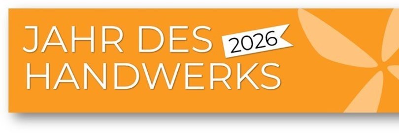 Werbebanner auf orangefarbenem Hintergrund. Links steht in großer weißer Schrift „Jahr des Handwerks“, darüber ein kleines weißes Schild mit der Jahreszahl „2026“. Rechts ist ein dekoratives, helles grafisches Motiv in Form einer stilisierten Blüte oder eines Windrades dargestellt.