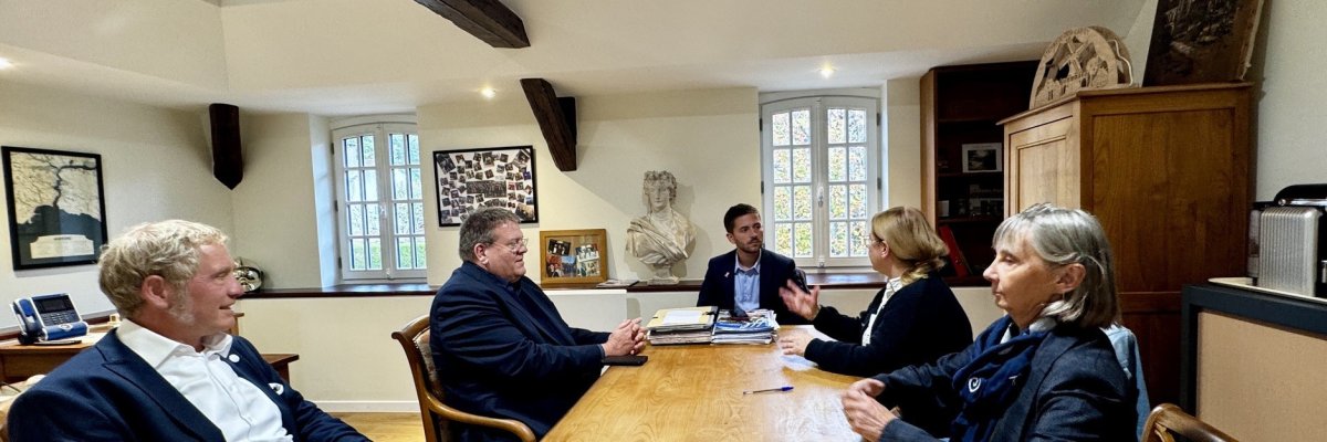 Fünf Personen sitzen bei einem Gespräch zur Städtepartnerschaft an einem langen Holztisch im Rathaus der französischen Partnerstadt Lardy.