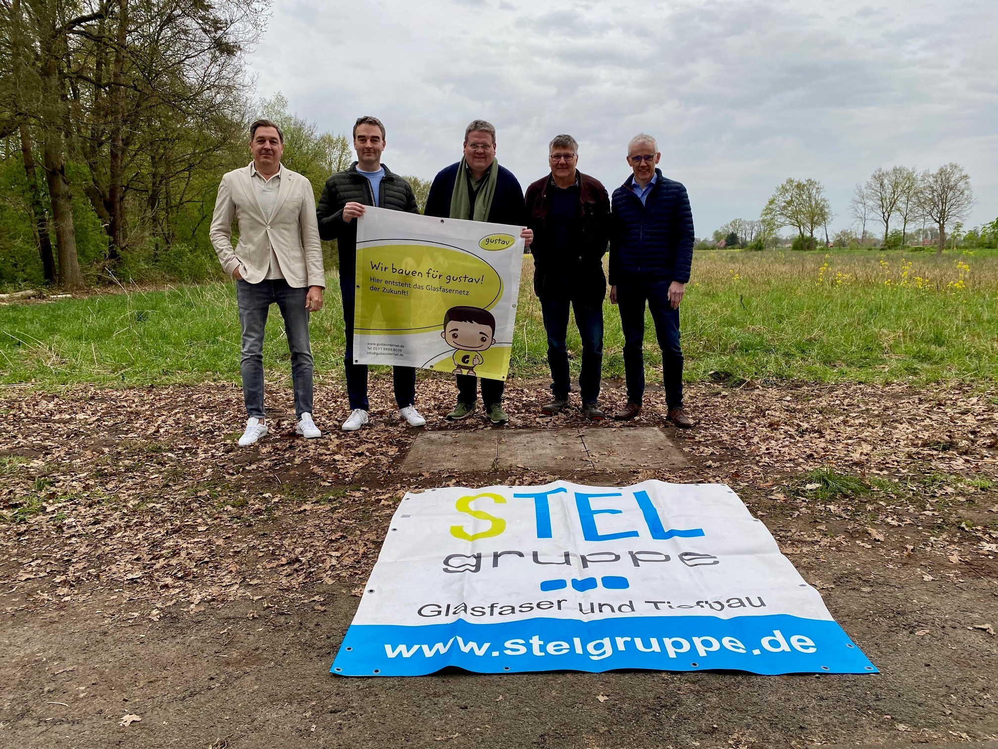 Gruppenfoto mit fünf Männern die ein Banner hoch halten, das auf den Glasfaserausbau in Stemwede hinweist.