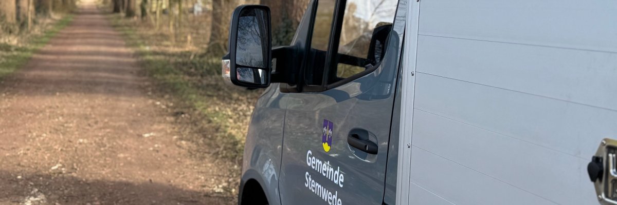 Ein Fahrzeug der Gemeinde Stemwede steht auf einem Waldweg, umgeben von Bäumen.