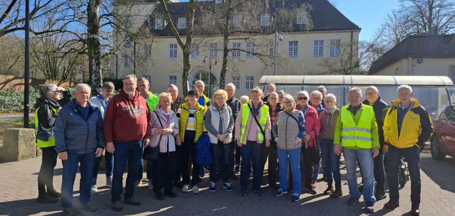 Eine Gruppe von Personen, die zum Teil Warnwesten tragen, stehen vor einem historischen Gebäude.