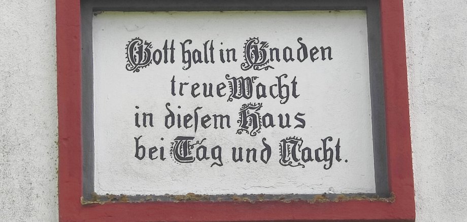 Ein Schild mit dem Spruch "Gott halt in Gnaden treue Wacht in diesem Haus bei Tag und Nacht."