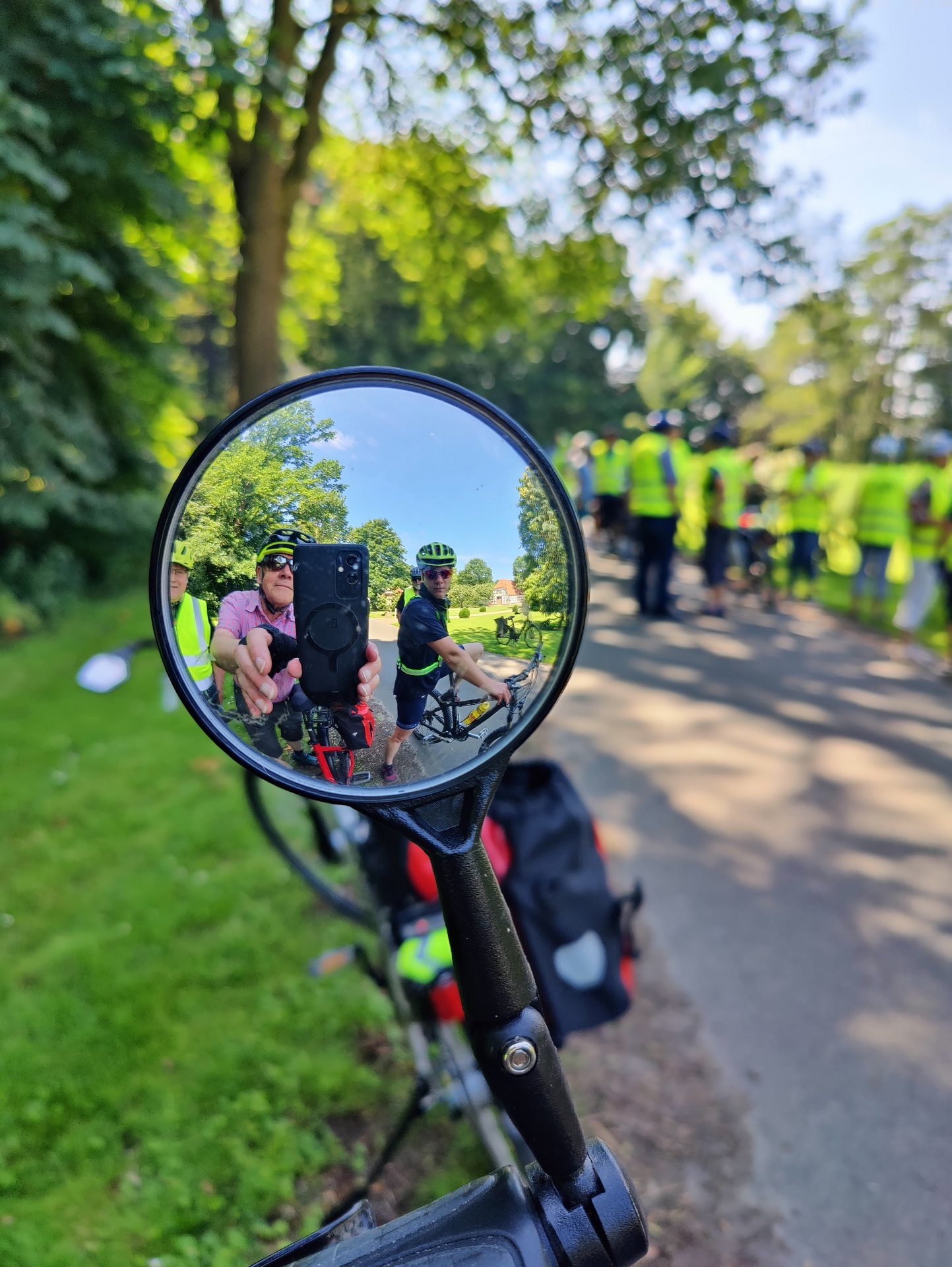 ZWAR Ein Fahrradfahrer, der mit seinem Handy ein Foto aufnimmt, in dem er in den Fahrradspiegel fotografiert.